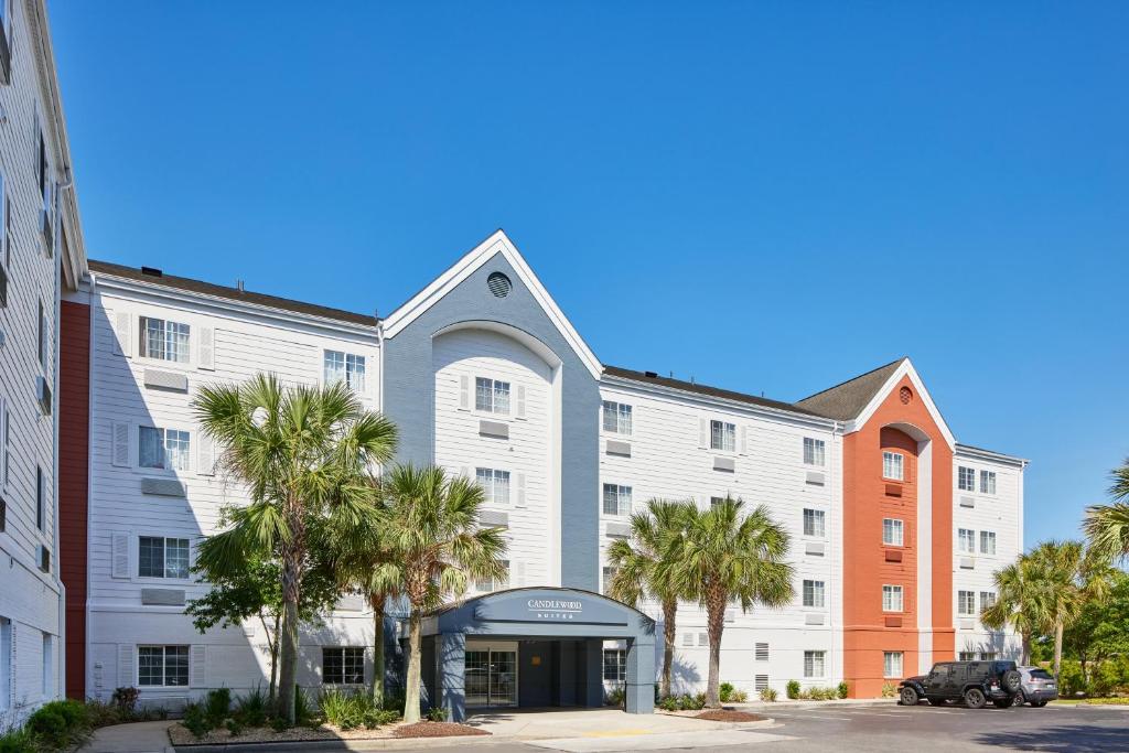 un grand bâtiment blanc avec des palmiers devant lui dans l'établissement Candlewood Suites Charleston-Northwoods, an IHG Hotel, à Charleston