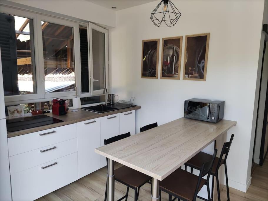 a kitchen with white cabinets and a wooden table at Studio entre lac de Monteynard et Gresse-en-Vercors in Monestier-de-Clermont