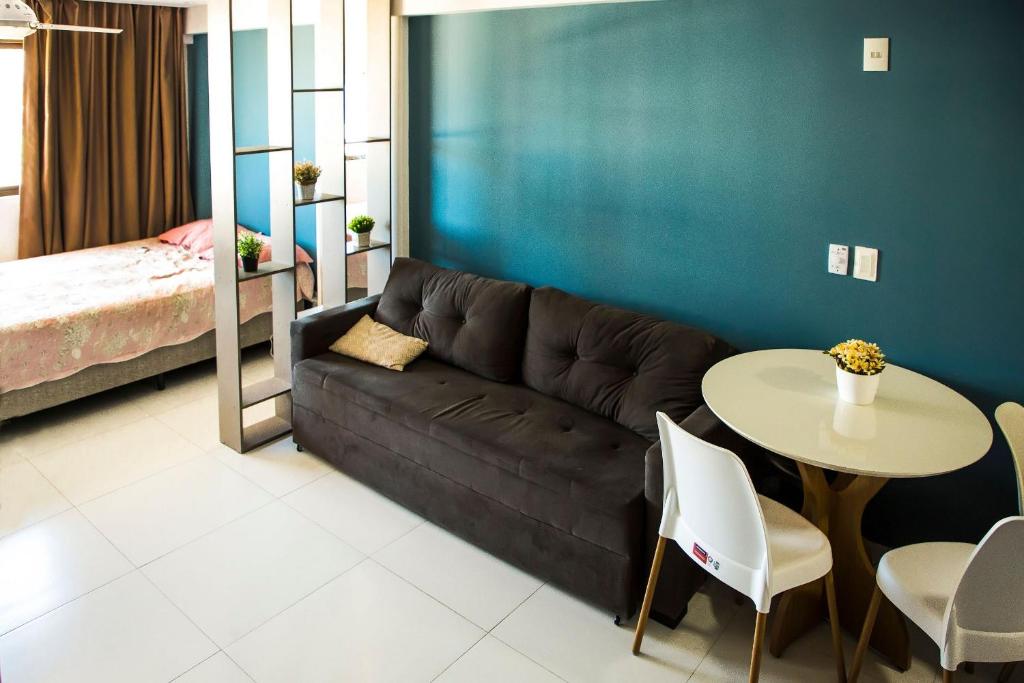 uma sala de estar com um sofá, uma mesa e uma cama em Studio Beira Mar - Sem Taxas em Recife