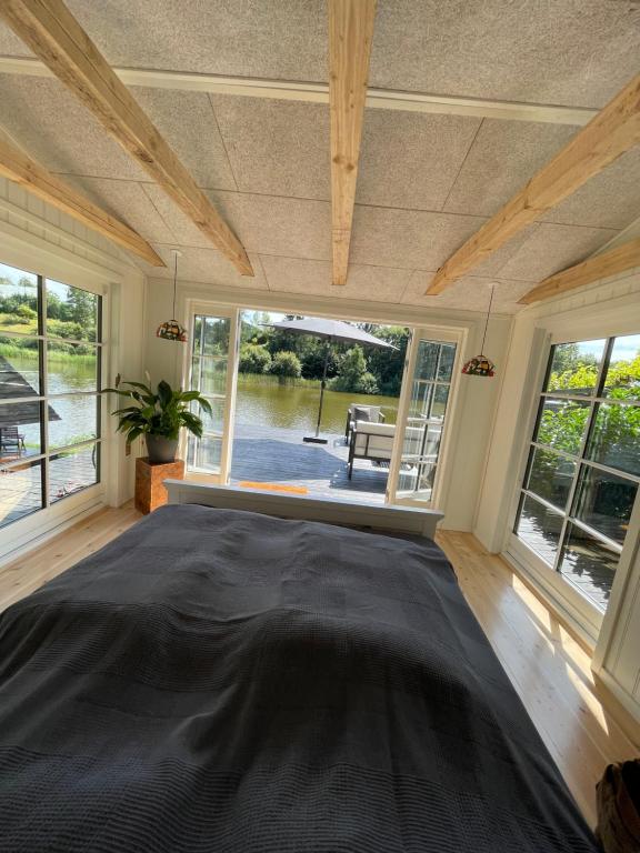 Un dormitorio con una gran cama negra en una habitación con ventanas en Hyggelig sommerhus. med udsigt, til vand fra senge en Veksø