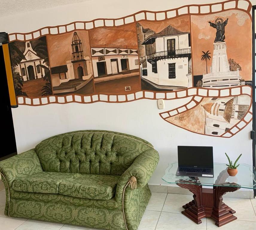 a green couch in a room with a wall with a picture at Hotel San Cayetano in Ocaña