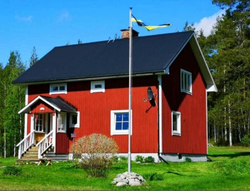 a red house with a flag in front of it at ,,Björklunda" cozy apartment in swedish lapland in Lycksele