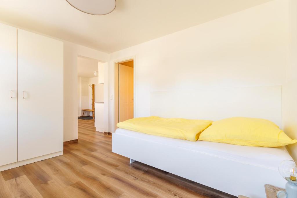 a bedroom with white walls and a bed with yellow sheets at Alte Bäckerei Zieglmeier - Wohnen auf Zeit in Oberdolling