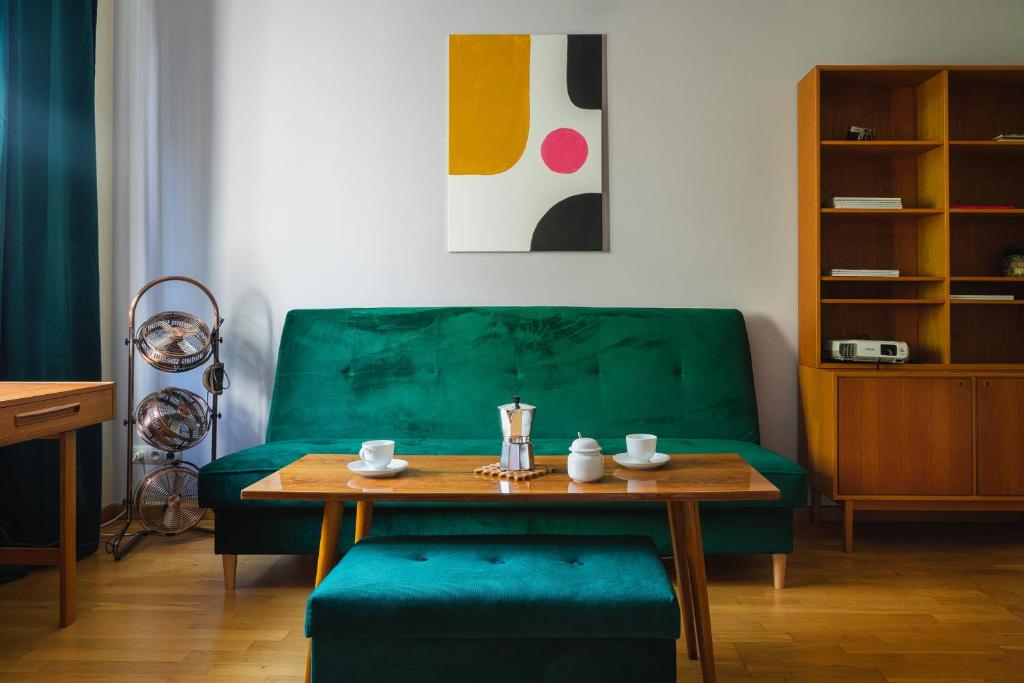 a living room with a green couch and a wooden table at Warsaw Concierge Racławicka in Warsaw