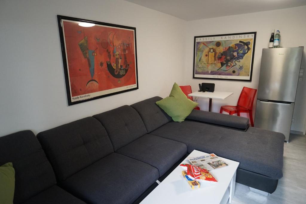 uma sala de estar com um sofá, uma mesa e um frigorífico em Neue und zentral gelegene Wohnung in Stuttgart em Stuttgart