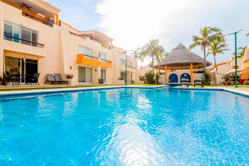 a swimming pool in front of a building with a gazebo at Relaxing Village, Acapulco Diamante, Rooftop in Acapulco