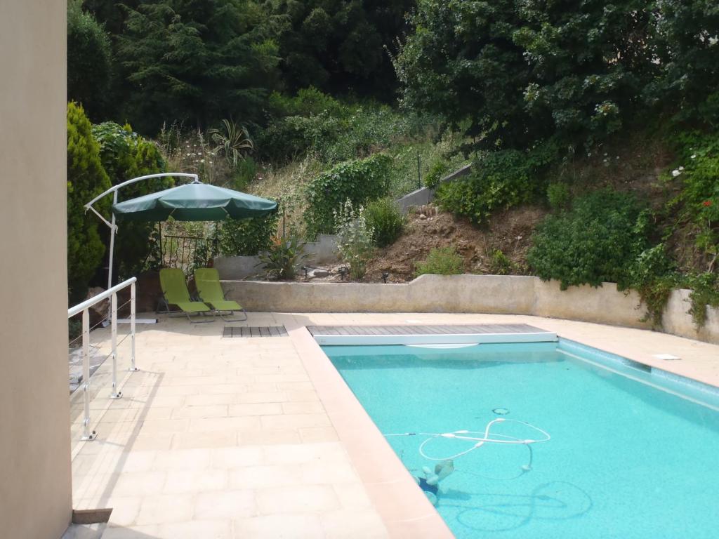einen Pool mit Sonnenschirm, Tisch und Stühlen in der Unterkunft Rose Niche in Cavalaire-sur-Mer