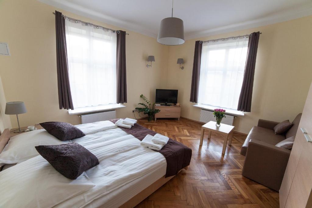 ein Schlafzimmer mit einem großen Bett und zwei Fenstern in der Unterkunft Place 4 You Apartments in Krakau