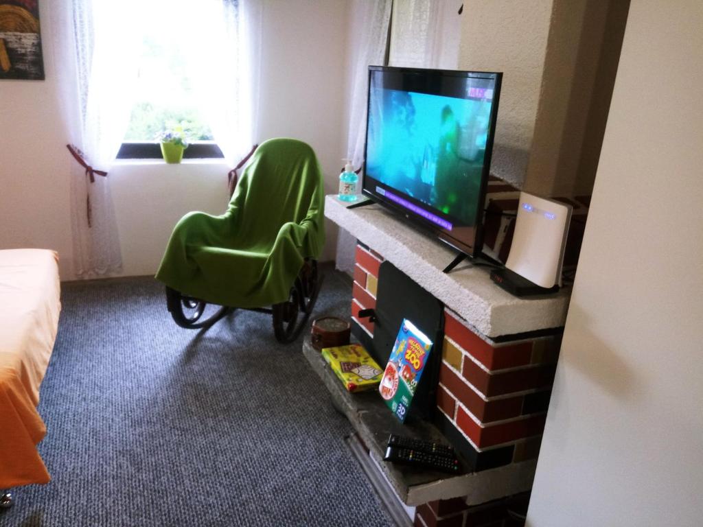 uma sala de estar com uma televisão e uma cadeira verde em Ravne Konak em Visoko