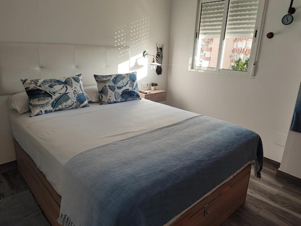 een slaapkamer met een groot bed met blauwe kussens bij Torremolinos Suite in Torremolinos