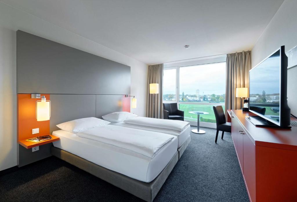 a hotel room with a bed and a desk and a television at Atlantic Hotel Galopprennbahn in Bremen