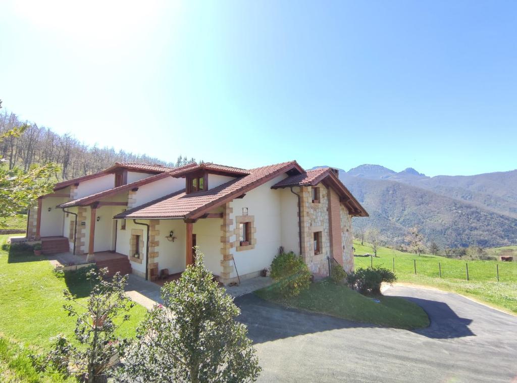 a house in a field with mountains in the background at La Huertona in Pesaguero-La Parte