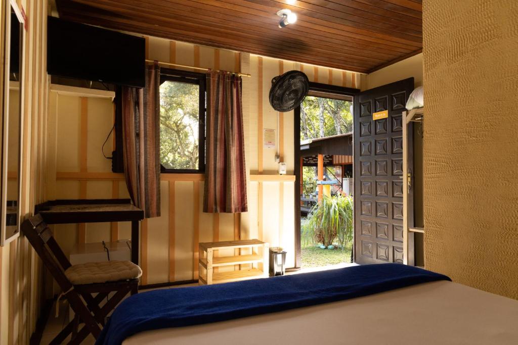 a bedroom with a bed and a door with a window at Pousada Recanto das Cores in Ilha do Mel