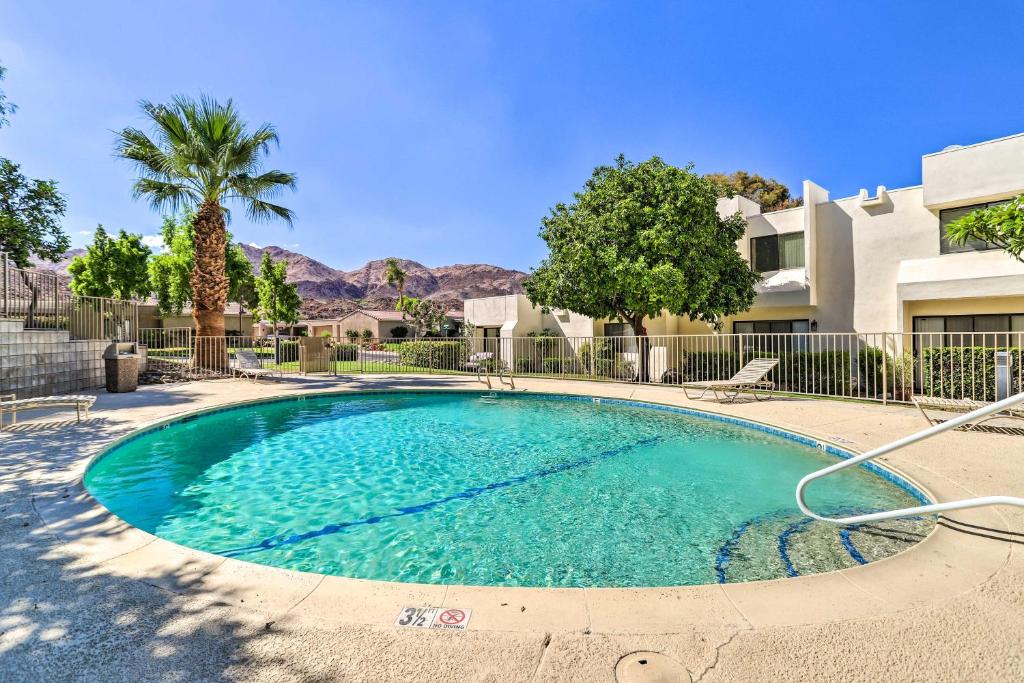 a swimming pool in front of a building with palm trees at Furnished Patio and Mtn View Palm Desert Retreat in Palm Desert