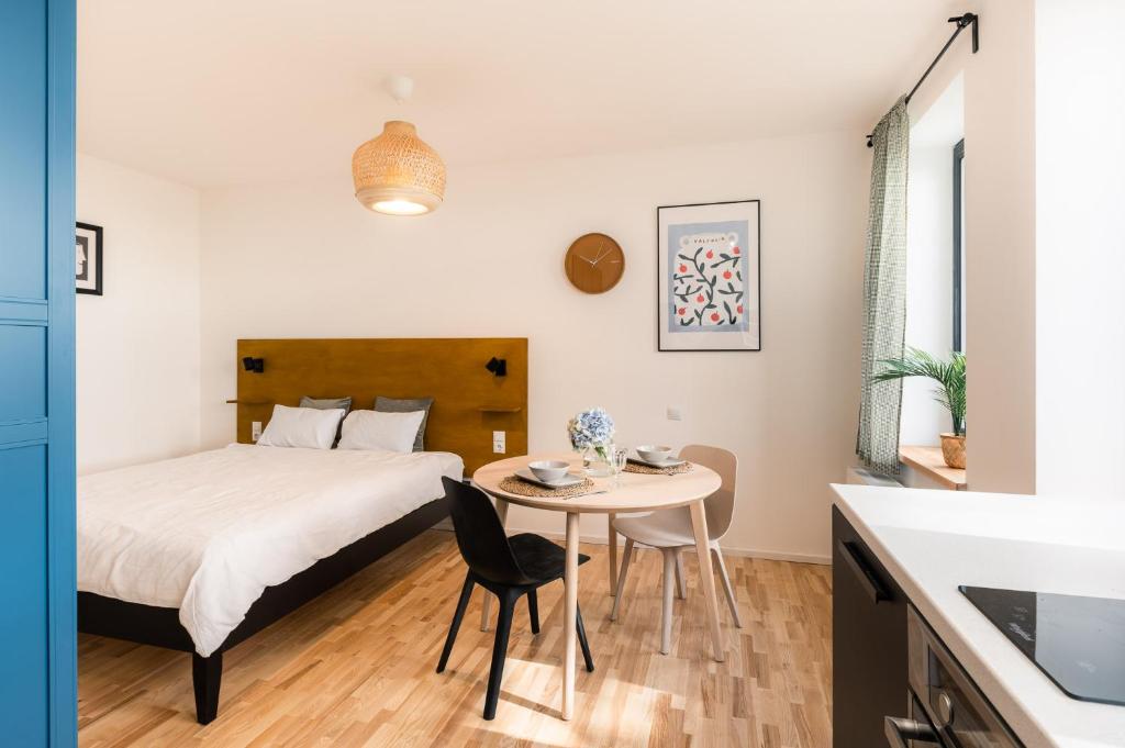 a bedroom with a bed and a table and a kitchen at Urban Condo in Liepāja