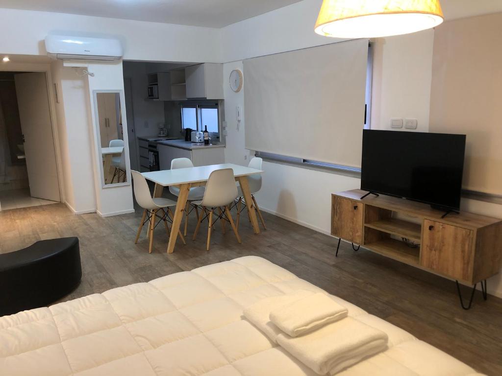 a living room with a television and a table with chairs at Cabildo Complete Suite in Buenos Aires