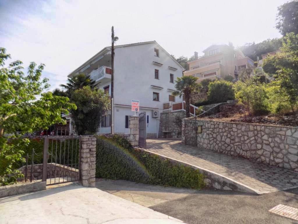una casa blanca en una colina con una valla en Studio Moscenice 7689a, en Mošćenička Draga