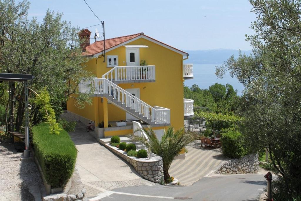 a yellow house with a staircase in front of it at Apartments with a parking space Medveja, Opatija - 7721 in Medveja