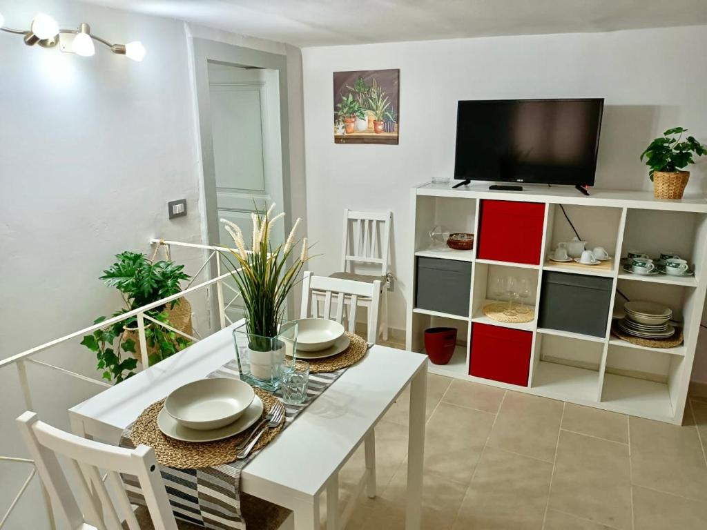 a dining room with a white table and a tv at L&L House in Catania