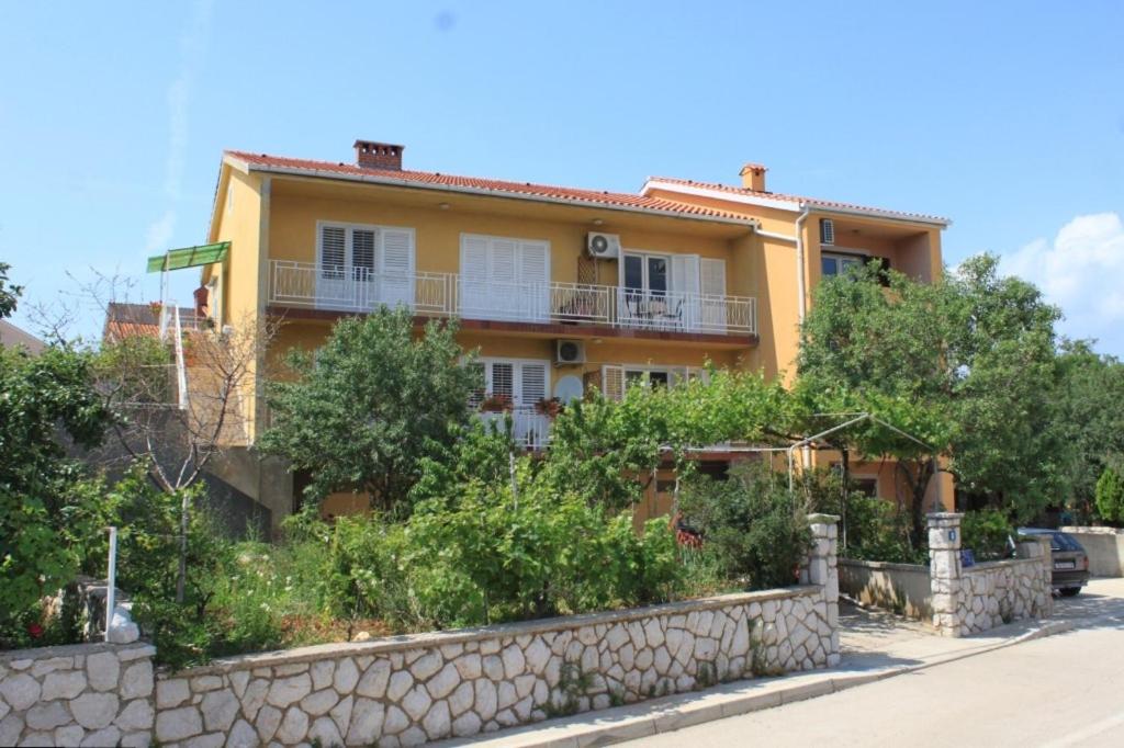 a yellow house with a stone wall and trees at Apartments with a parking space Cres - 7994 in Cres
