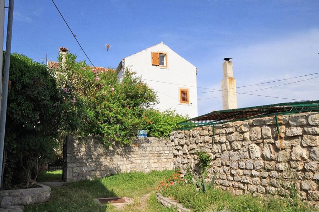 ein weißes Haus mit einer Steinmauer und einem Gebäude in der Unterkunft Holiday apartments Osor, Losinj - 8004 in Nerezine