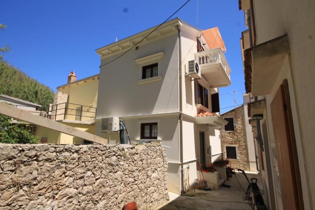 ein weißes Gebäude neben einer Steinmauer in der Unterkunft Apartment Susak 8047a in Susak