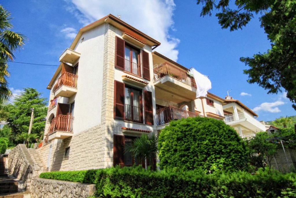 a large building with red windows and bushes at Apartments by the sea Icici, Opatija - 7745 in Ičići