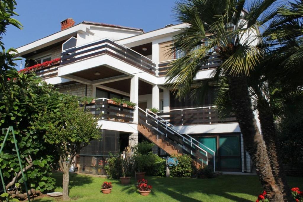 une grande maison blanche avec un palmier en face de celle-ci dans l'établissement Apartments with a parking space Opatija - 7831, à Opatija