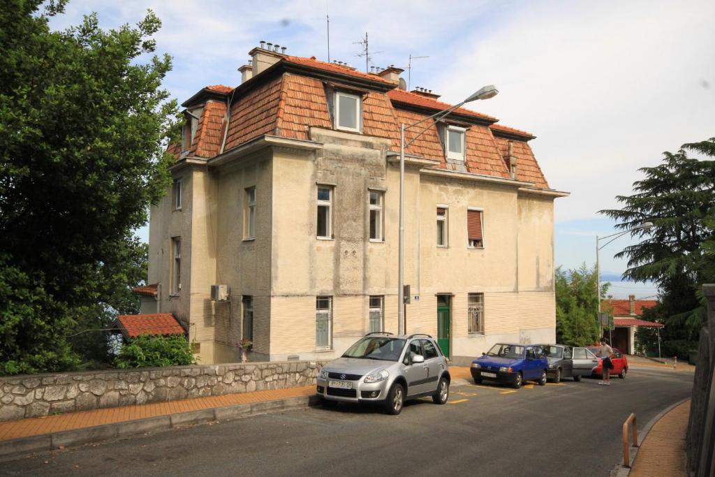 an old house with cars parked in front of it at Apartments with a parking space Opatija - 7868 in Opatija