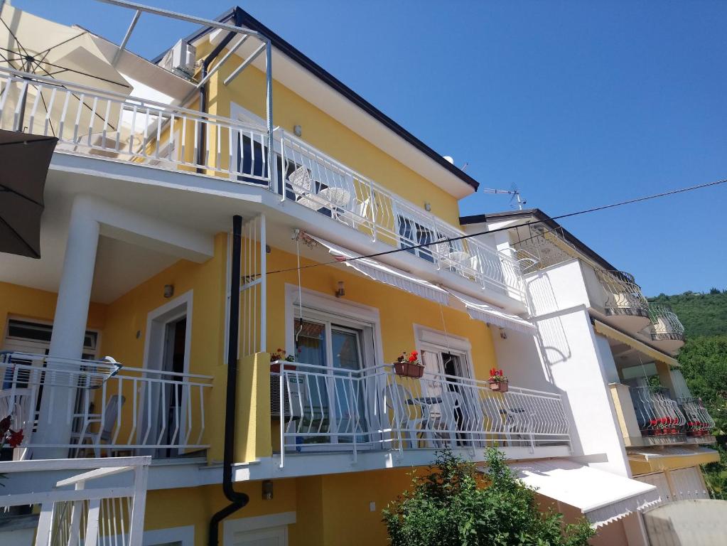 Apartments with a parking space Opatija - 7896 في أوباتيا: مبنى اصفر وابيض بشرفات بيضاء