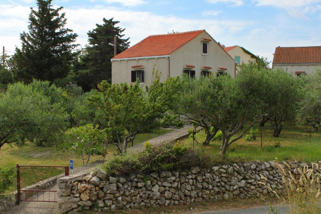 ein altes Haus mit einer Steinmauer und Bäumen in der Unterkunft Holiday house with a parking space Sveti Jakov, Losinj - 7950 in Nerezine