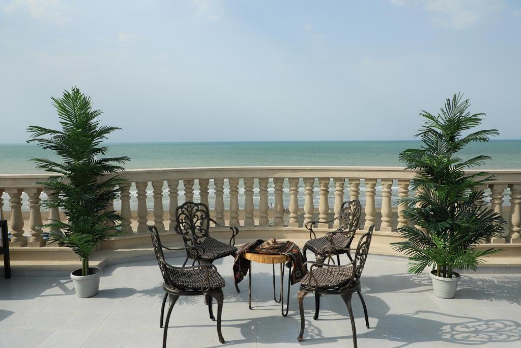 una mesa y sillas en un balcón con vistas a la playa en NovART SeaVilla&Gallery Hotel, en Sumqayit