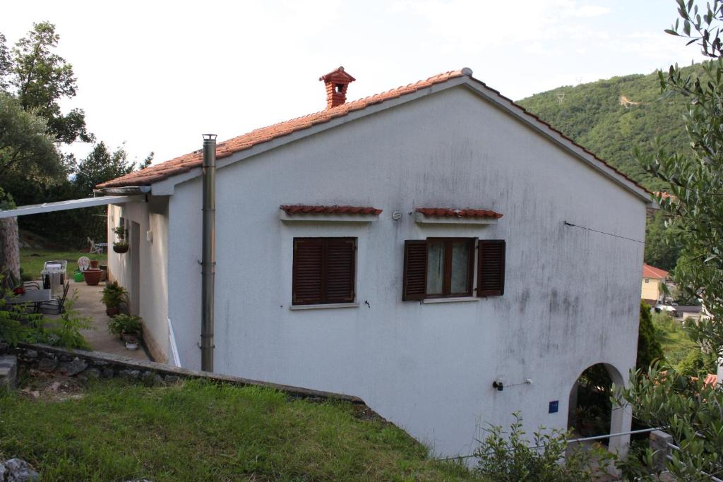 ein weißes Haus mit braunen Fensterläden darauf in der Unterkunft Apartments with a parking space Moscenicka Draga, Opatija - 7786 in Mošćenička Draga