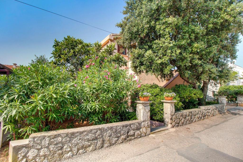 Čunski的住宿－Apartments by the sea Artatore, Losinj - 7934，房屋前方有植物和花卉的挡墙