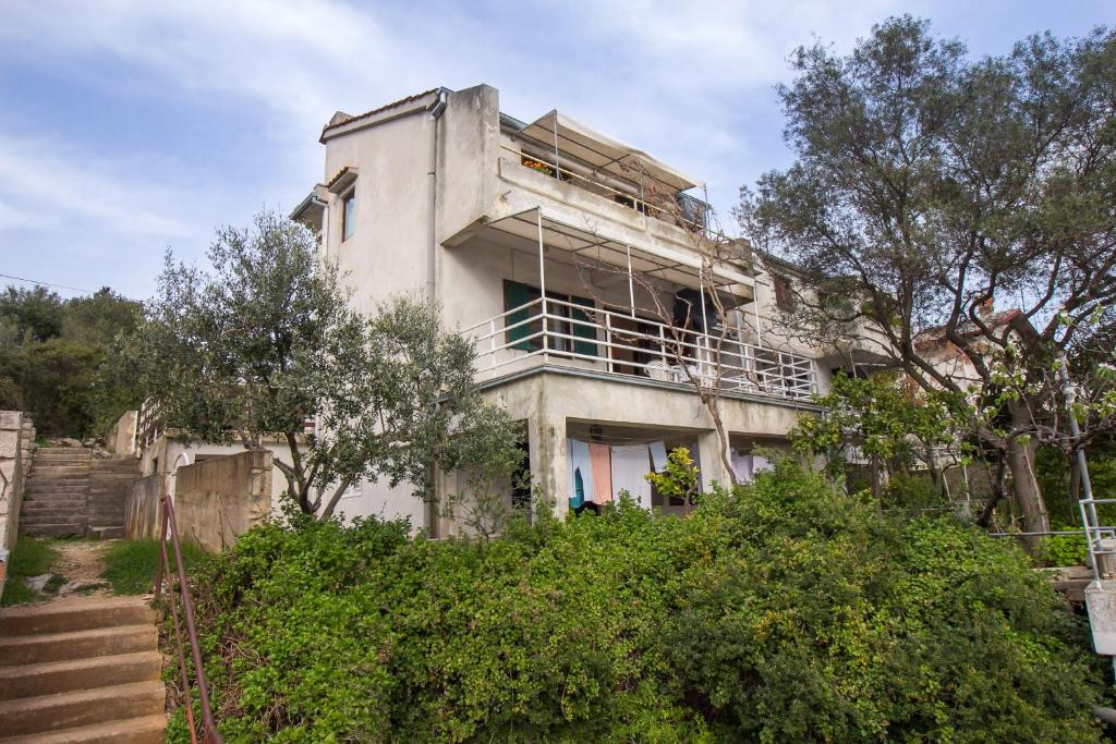 stary biały budynek ze schodami i drzewami w obiekcie Apartment Mali Losinj 7942a w miejscowości Mali Lošinj