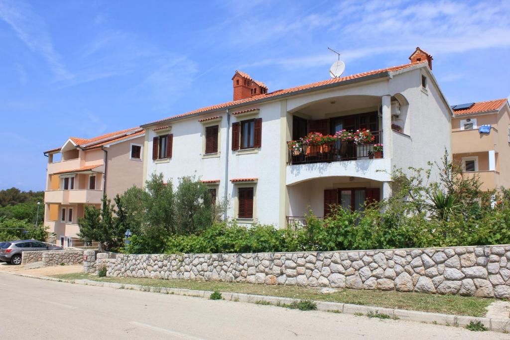 a white building with a stone wall next to a street at Apartments with a parking space Cres - 7983 in Cres