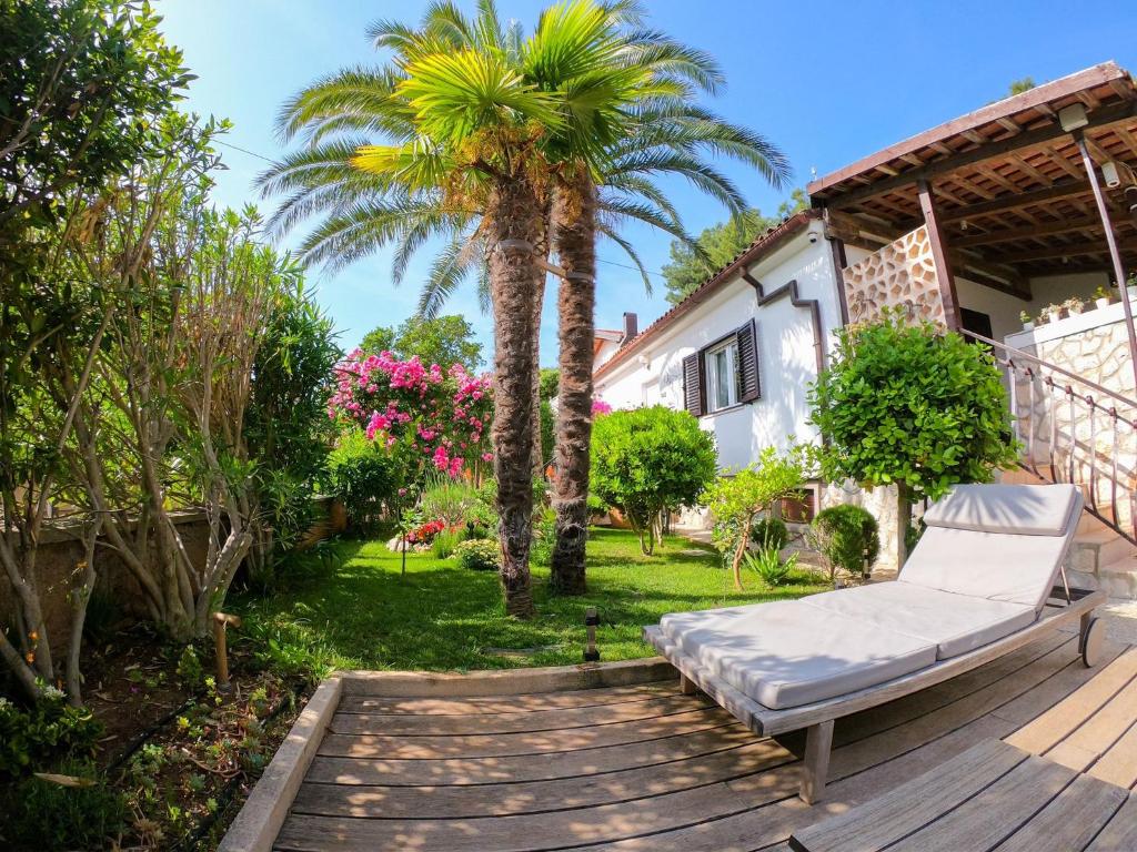 a bed on a deck next to a palm tree at Apartments by the sea Artatore, Losinj - 8020 in Čunski