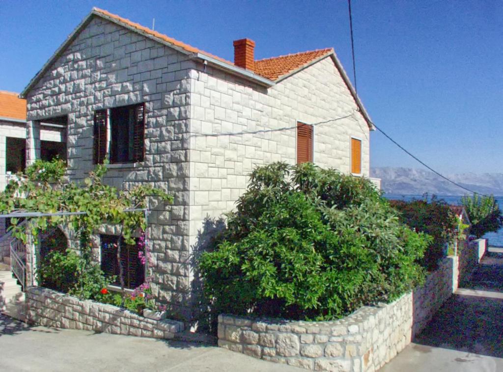 a small stone house with bushes in front of it at Apartments by the sea Postira, Brac - 9241 in Postira