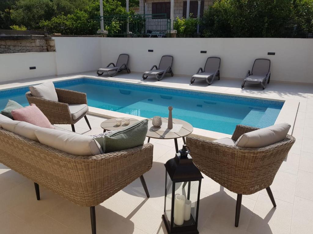 a swimming pool with chairs and a table next to a pool at Seaside apartments with a swimming pool Lumbarda, Korcula - 9303 in Lumbarda
