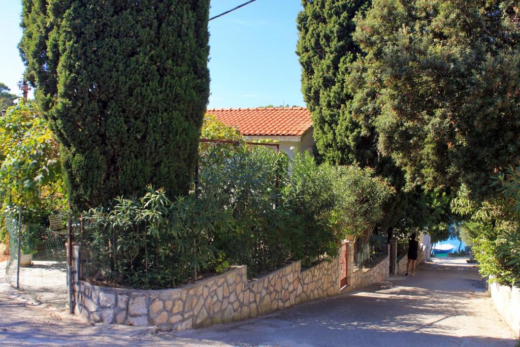 a stone wall with bushes and trees on a street at Apartments by the sea Brna, Korcula - 9231 in Smokvica