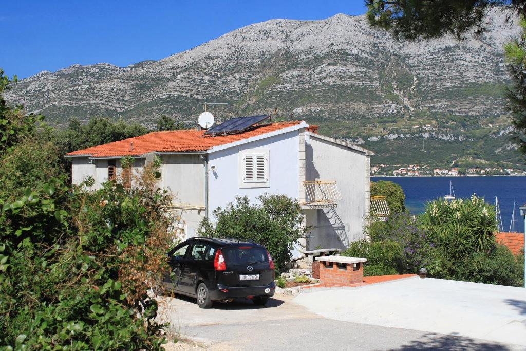 a car parked in front of a house with a mountain at Apartments and rooms by the sea Korcula - 9267 in Korčula