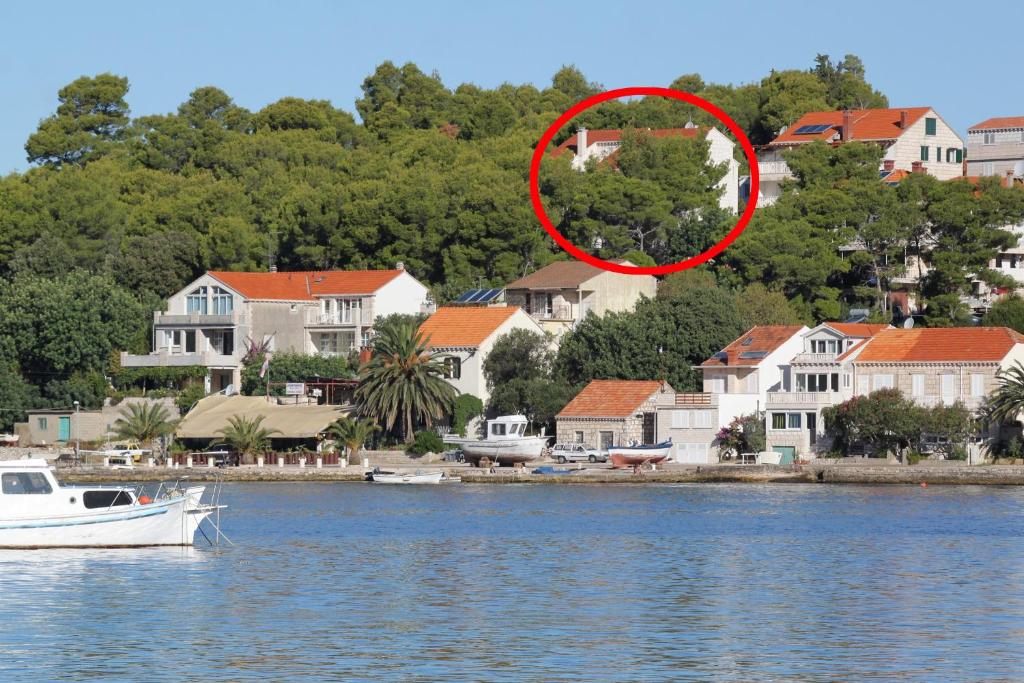 a boat in the water next to a group of houses at Apartments by the sea Lumbarda, Korcula - 9304 in Lumbarda