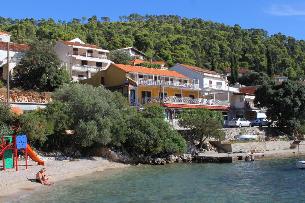 a woman sitting on a beach next to the water at Apartments by the sea Brna, Korcula - 9162 in Smokvica