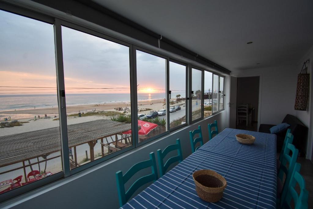 Un comedor con mesa y vista a la playa. en Rock’s Beach Spot Front, en Costa da Caparica