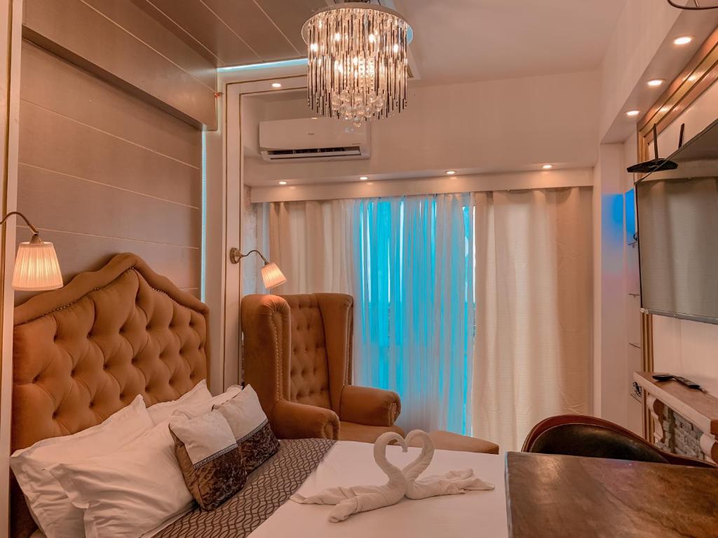 a room with a bed and a chair and a chandelier at GoldenSuites at CoolSuites WindResidences Tagaytay in Tagaytay