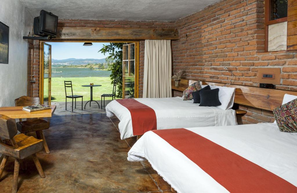 een kamer met 2 bedden en een bakstenen muur bij Hotel El Remanso Tapalpa in Tapalpa