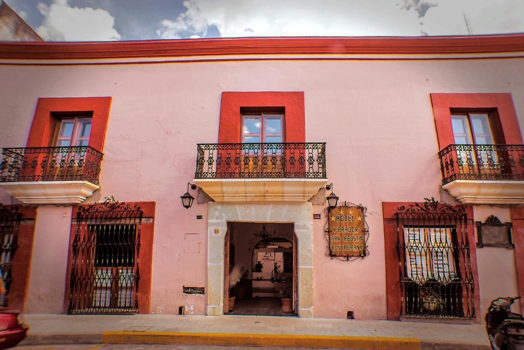 オアハカにあるパラドール サン アグスティンのバルコニーと出入り口が備わるピンク色の大きな建物