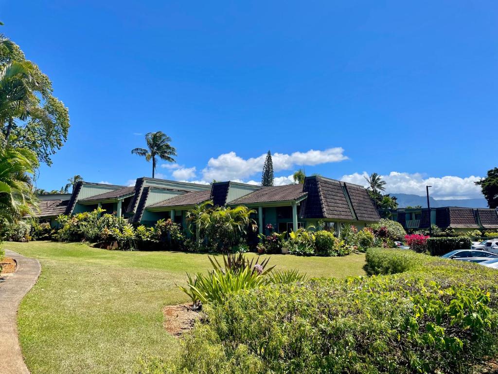 a house with a green yard with bushes at Puamana Maluhia - Two Bedroom / Two Bath Condo in Princeville