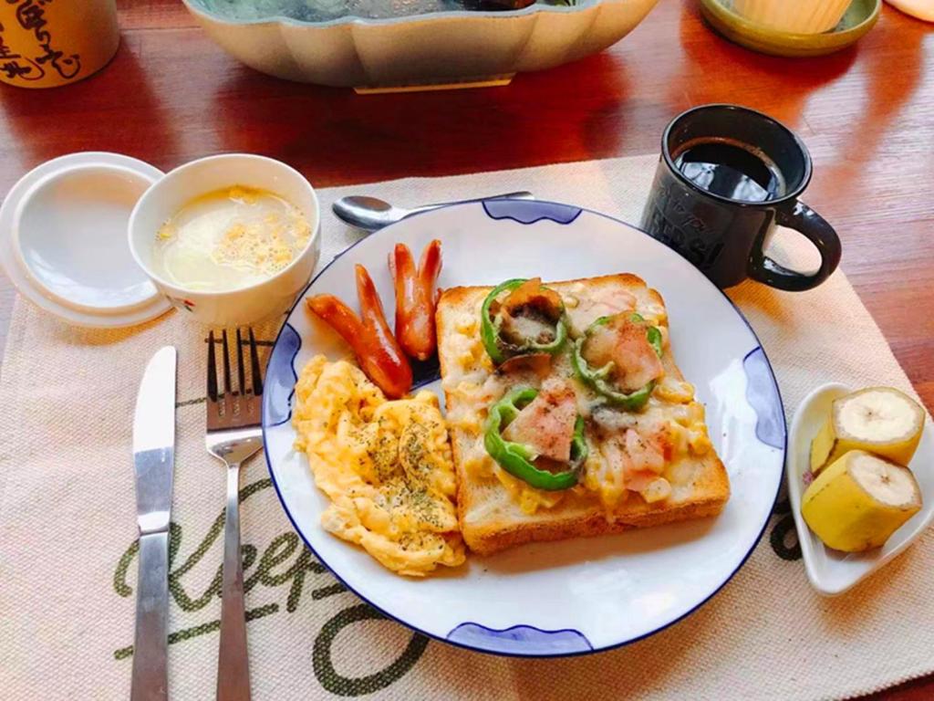 une assiette de nourriture avec une tranche de pizza et de carottes dans l'établissement Pension Marieペンションマリエ, à Yamanakako