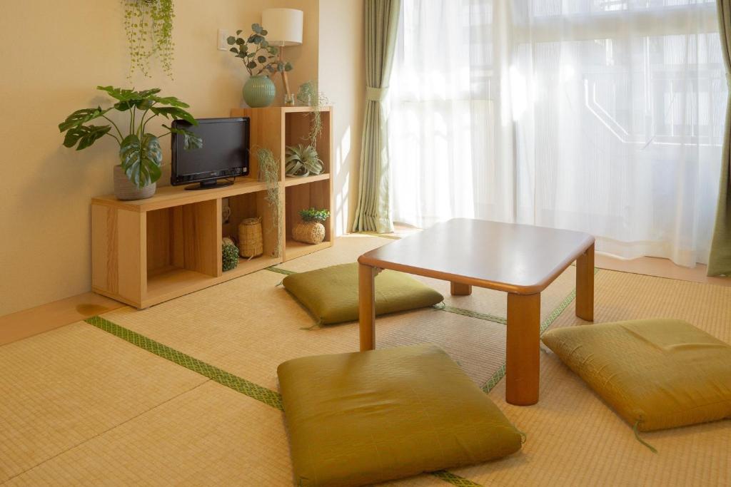 een woonkamer met een tafel en twee poeven en een tv bij Shinjuku-Kabukicho-507 in Tokyo
